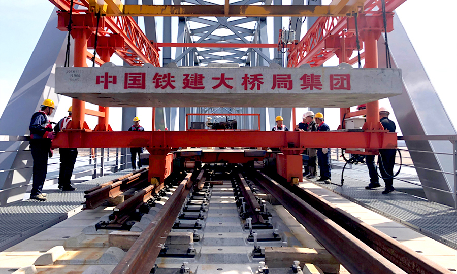 同江中俄铁路大桥是中国首座跨境四线套轨板式无砟轨道铁路大桥，可适应中俄两国不同规格的轨距。大桥无砟轨道板为四线套轨板式结构，俄方轨距线路在左为1520mm，国内轨距线路在右为1435mm，两者相差85mm。该板型为国内外首次采用。图为中国铁建大桥局四公司同江中俄铁路大桥项目中俄交界最后144米铺轨。