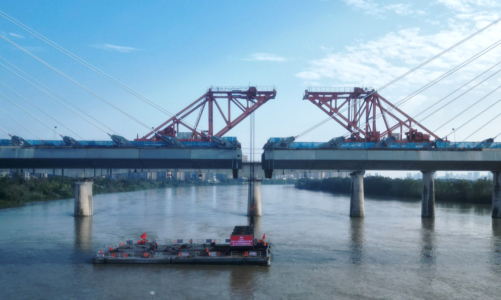 遂宁涪江特大桥是全线“3隧4桥”重难点控制性工程之一，大桥全长5585.4米。主桥为“H”型特殊结构双塔双索面钢混结合梁斜拉桥，主跨长305米，在双塔双索面钢混结合梁斜拉桥中主跨长度位居西南第一，全国第二。图为大桥钢箱梁吊装作业现场。