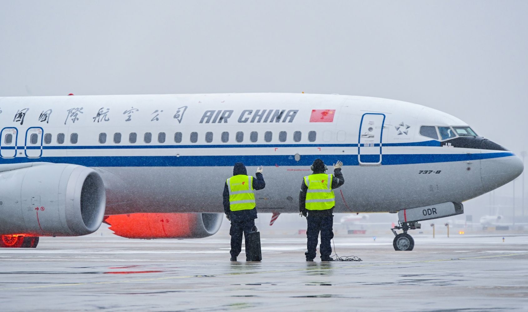 在北京首都国际机场，中航集团一线工作人员目送完成除冰雪作业的飞机缓缓出港。