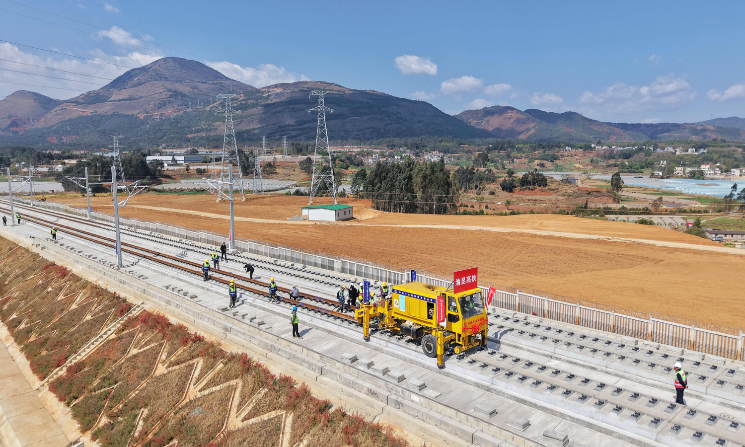 渝昆高铁云南段线路纵贯云贵高原乌蒙山腹地，地质地貌错综复杂，桥隧比高达87.4%，超10公里的长大隧道多达10座。此次铺轨施工任务，涵盖上下行钢轨铺设846公里、无砟轨道道岔50组、无砟轨道钢轨伸缩调节器16组等工程。图为渝昆高铁铺轨现场。